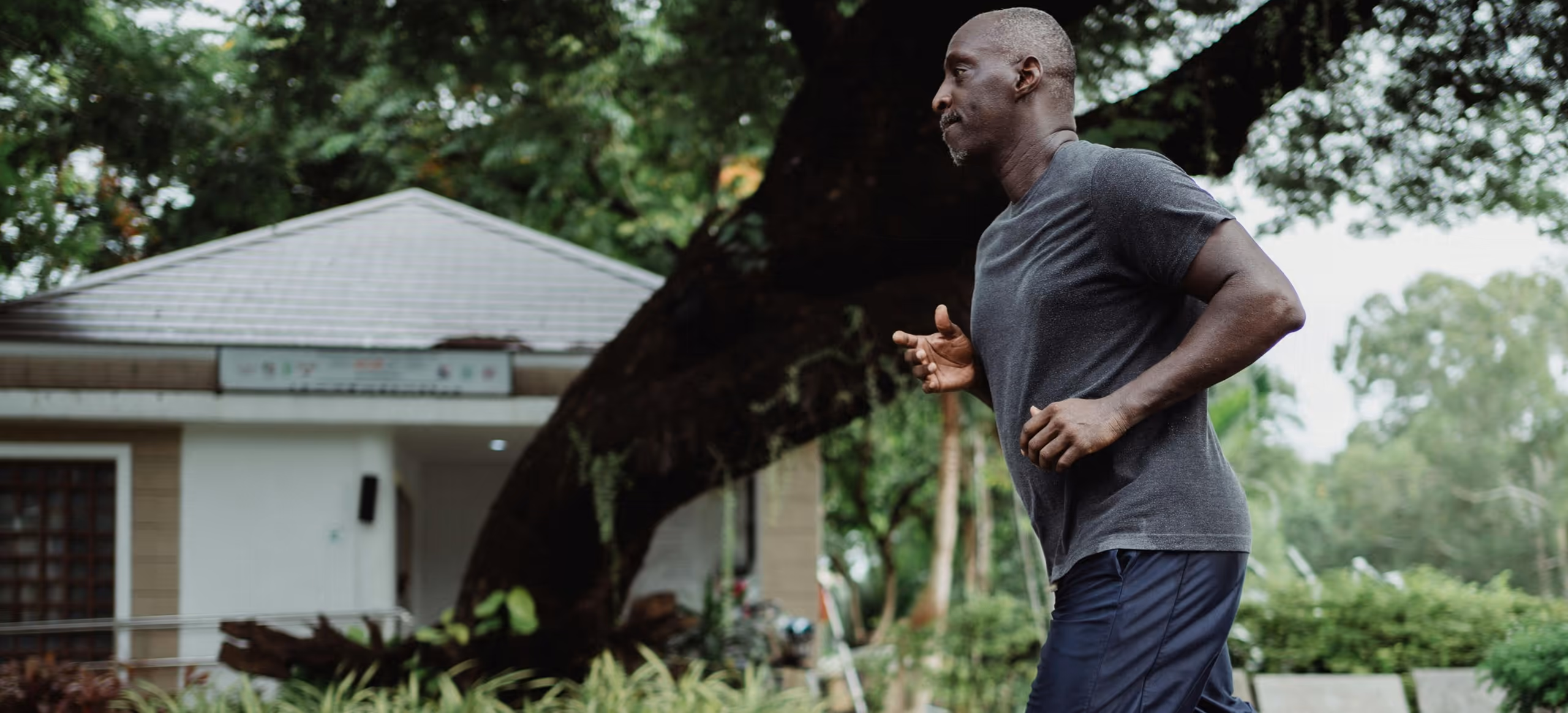 A man out for a run along a quiet residential street lined with trees